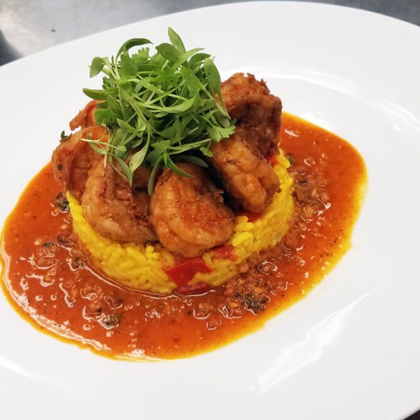 Shrimp in a circle placed on top of bed of rice on sauce